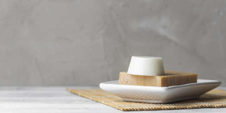 Handmade solid shampoo and conditioner bars in the soap dish over grey background. Copy space for...