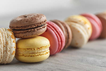 Colorful macaroon cakes in a row over grey background