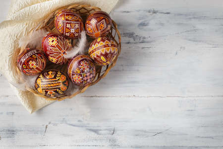 Pysanky, Ukrainian Easter eggs decorated with wax-resist dyeing technique, white wooden background,...