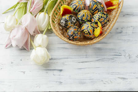 Pysanky, Ukrainian Easter eggs decorated with wax-resist dyeing technique, tulip flowers on white wooden background, copy space for textの写真素材