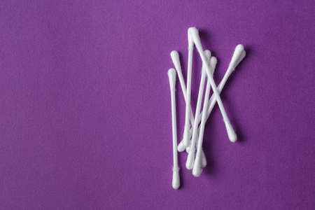 White plastic cotton swabs on vivid purple background