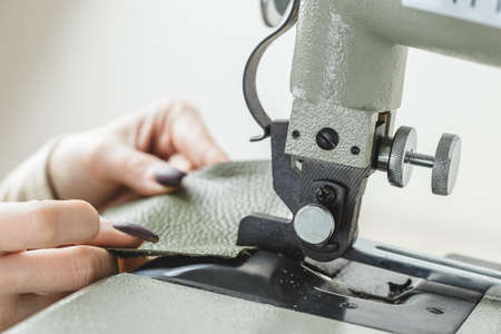 Young white woman stitching leather using a sewing machineの写真素材