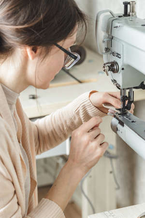 Young white woman stitching leather using a sewing machine
