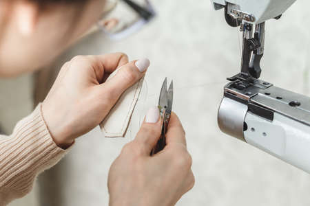 Young white woman stitching leather using a sewing machineの写真素材