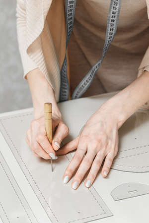 Leather craftswoman working making measuremets in patterns at table in workshop studio. Small business and mastership conceptの写真素材