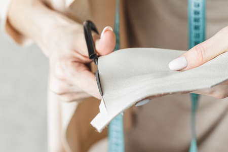 Female handbag designer measuring leather and cutting out details in a workshop studio