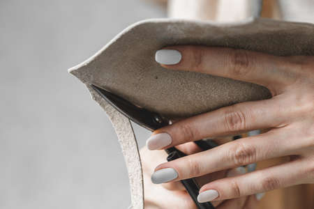 Female handbag designer measuring leather and cutting out details in a workshop studio
