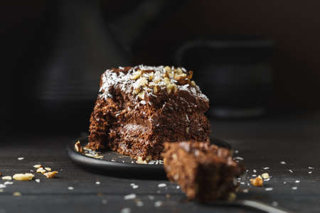 A piece of delicious chocolate cake in black plate on wooden table background, closeupの写真素材