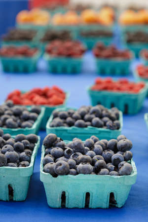 Blueberries, bilberries and raspberries in paper box containers on food farmers marketの写真素材