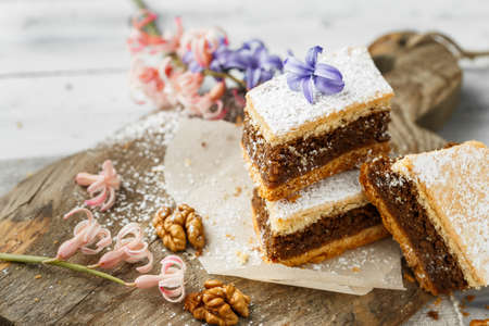 Homemade walnut pie with sugar icing cut to pieces ready to eat. Dessert served on a wooden board