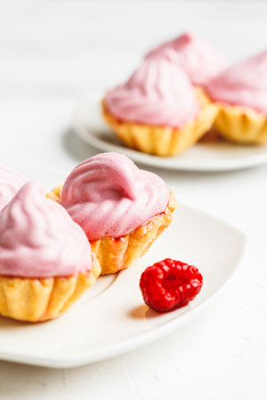 Mini cakes baskets with raspberry cream served on white plateの写真素材