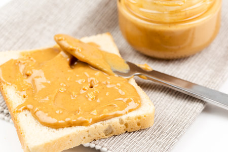Crunchy peanut butter spreading on a toast, close up