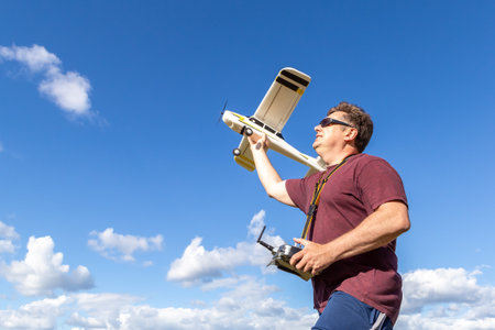 Middle-aged man launching a model of the radio remote controlled airplane outdoor on a background of the skyの写真素材