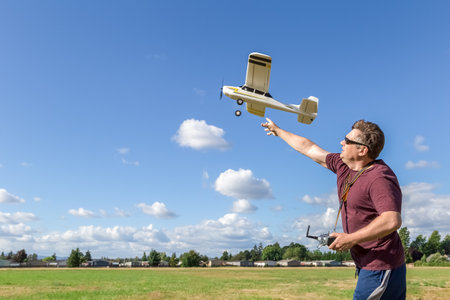Middle-aged man piloting a model of the radio remote controlled airplane outdoor on a background of...