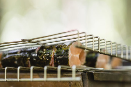 Cooking fresh trout fish on charcoal grill. Barbeque party outdoorsの写真素材