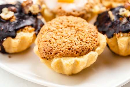 Sweet mini tart served on white plate. Homemade tasty tartlets with walnuts. Tartelette close upの写真素材