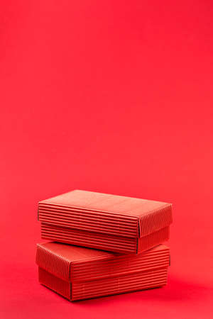 Monochromatic photo of two red closed corrugated cardboard boxes on red background. Valentine's Day gift packaging conceptの写真素材
