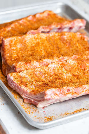 The hand of a male chef puts salt and spices on the raw piece of beef ribs meat. Raw St Louis Style BBQ Ribs with Rub Ready to Cookの写真素材