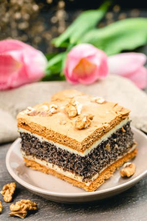 Piece of homemade poppy seed cake on a plate with pink tulips, rustic style, soft focusの写真素材