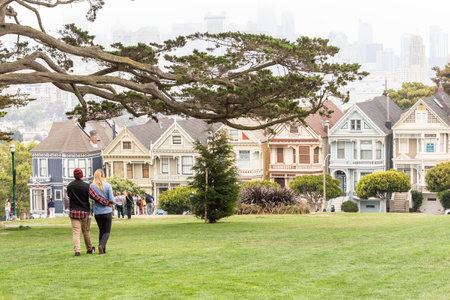 SAN FRANCISCO, CALIFORNIA - July 24, 2018: A couple of tourists enjoying the view of Painted Ladies, colorful Victorian houses in a row on a summer day, San Francisco, California, USAのeditorial素材