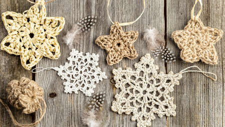 Winter or Christmas wooden background with crocheted stars and snowflakes. Handmade Christmas decorations made of natural materials. Top view, flat lay.の写真素材