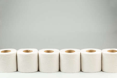 A Row of Toilet Paper Rolls over Gray Background with Copy Space for text