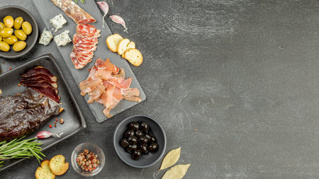 Set of various kind of smoked sliced cured meat. Duck breast, jerky ham and traditional dried sausage on black board. Copy Space for textの写真素材