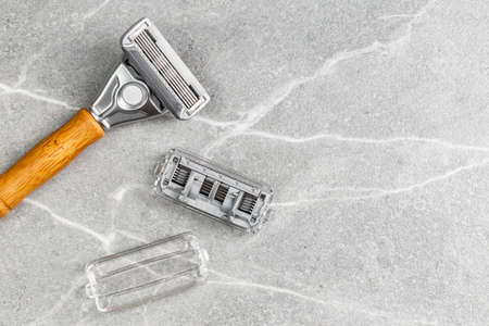 Shaving Razor with wooden handle with refill blade on a grey marble background. Plastic free hygiene toolの写真素材