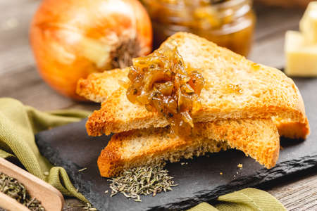 Onion confiture on a toast bread on a wooden table. Onion jam homemade preservationの写真素材