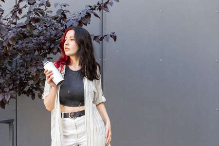 Young woman opening white reusable insulated teavel mug for coffee to go in her hands.