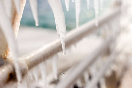 Frozen jetty at the sea with icicles hanging at the metal handrails. Shallow depth of fieldの写真素材