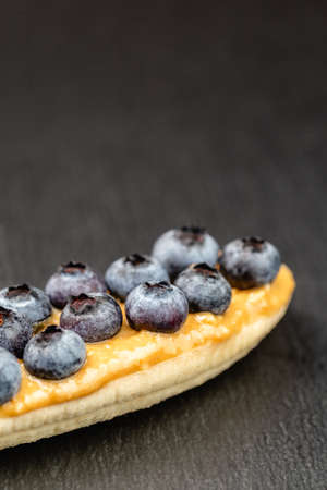 Healthy appetizers with sliced bananas with peanut butter spread and blueberries on the top on the slate plate, space for textの写真素材