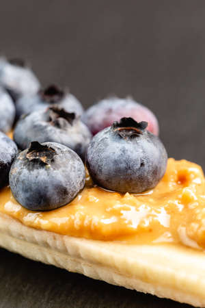 Healthy appetizers close up with sliced bananas with peanut butter spread and blueberries on the topの写真素材