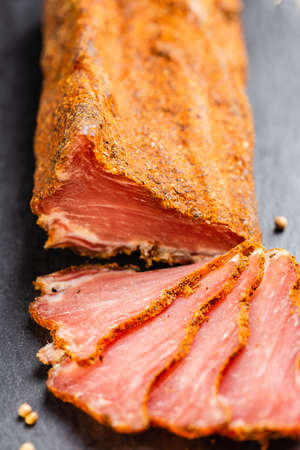 Dry Cured Pork Tenderloin on the slate serving board. Lonzino, jerky tenderloin appetizer on wooden background.の写真素材