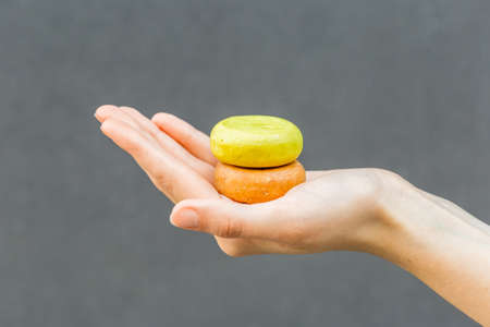 Woman hands holding organic soap or solid shampoo with no packaging over gray background. Healthy lifestyle, beauty, skin care, Zero waste concept.の写真素材