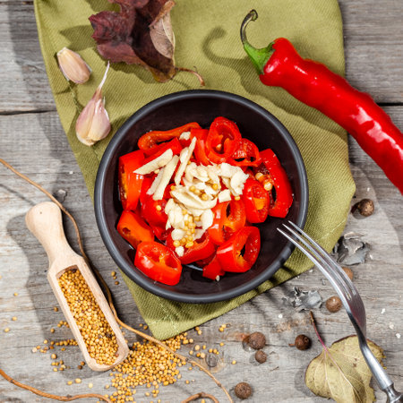Chopped and pickled Red Hot Chili Pepper Canning Appetizer with garlic and mustard served in a black bowl on the wooden rustic style tableの写真素材