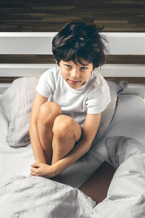 Little boy suffering from sleep disorder sitting in his bedの写真素材