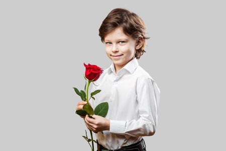 Six years old boy holding a red rose as a gift for his Valentine. Celebrating St. Valentineâs Day or Motherâs Day.の写真素材