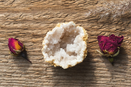 Quartz in Geode mineral stone with dry roses on wooden backgroundの写真素材