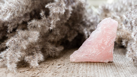 Rose quartz mineral specimen on wooden background. Rose quartz is a healing pink stone good to...