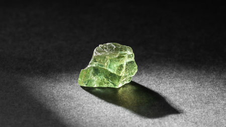 Translucent green Apatite crystal healing stone on dark background backlit from behind. Natural...