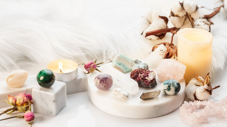 Minerals Collection on White Marble Stand with Burning Candles and Dry Flowers. Healing Stones for Wicca Witchcraft Practice. Copy Space for Textの写真素材