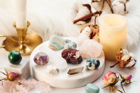Minerals Collection on White Marble Stand with Burning Candles and Dry Flowers. Healing Stones for Wicca Witchcraft Practice on White Marble Standの写真素材