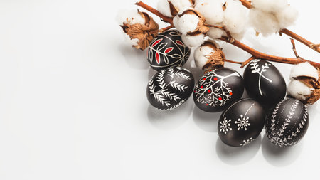 Black and White Pysanka Easter Eggs Decorated with Traditional Eastern European Beeswax Technique and a Branch of Cotton Flower. Greeting Card with Space for Textの写真素材