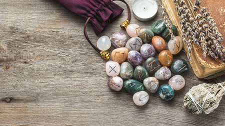 Elder Futhark Rune Stones Set Made of Natural Gemstones with Old Book, Dry Herbs and Sage Incense on Wooden Background with Copy Spaceの写真素材