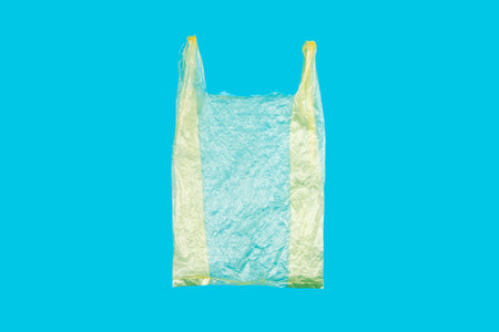 Yellow Single-use Plastic Shopping Bag on Blue Background. This kinD of Grocery Bags are Forbidden in Several Countriesの写真素材