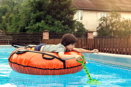 Six Years Old Boy Swimming in the Tube in the Water Pool. Summer Activities for Children and Water Safety Conceptの写真素材
