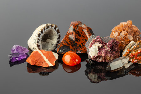 Close up photo of the Group of Stones and Minerals including Red Jasper, Aragonite Sputnik, Erythrite Crystals, Mahogany Obsidian and Agate Geode on Reflective Surfaceの写真素材