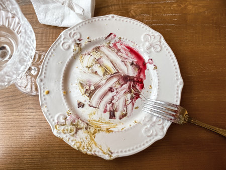 Dirty Plate After Eaten Dessert on the Wooden Table with Fork, Empty Glass and Used Napkinの写真素材