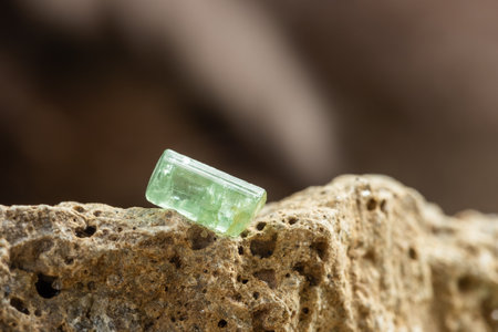 Raw Green Tourmaline Crystal on Rough Stone Background in Natural Lightの写真素材